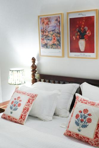 a bed with red and white pillows and pictures on the wall at Aurora Luxe Residence in Jaipur