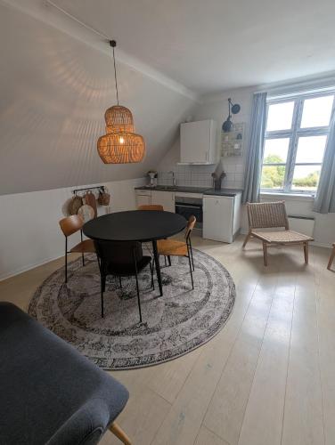 a living room with a table and chairs and a kitchen at Villa Koch X Pension Koch in Gudhjem