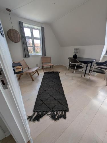 a living room with a black rug on a wooden floor at Villa Koch X Pension Koch in Gudhjem