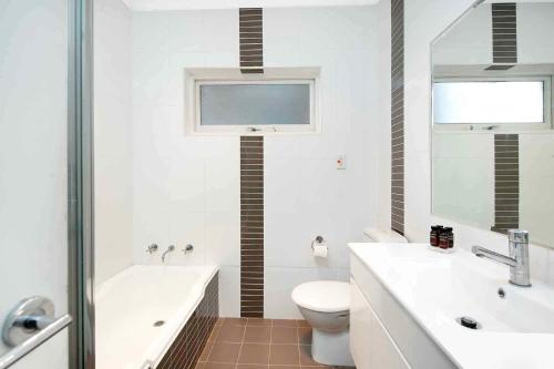a bathroom with a tub and a toilet and a sink at Beach-Front Apartments in Sydney