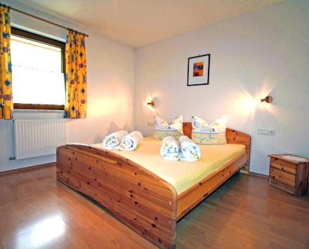 ein Schlafzimmer mit einem großen Holzbett mit Kissen in der Unterkunft Haus Stark in Pettneu am Arlberg