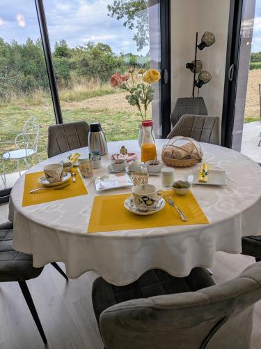 Una mesa blanca con servilletas amarillas y comida encima. en Coeur et Nature, en Colembert