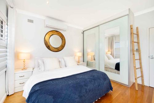 a bedroom with a large bed and a mirror at Beach-Front Apartments in Sydney