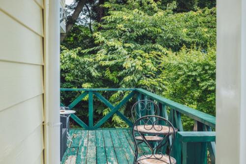 a balcony with two chairs and a table and trees at 伊豆集 Episode IZU in Ito