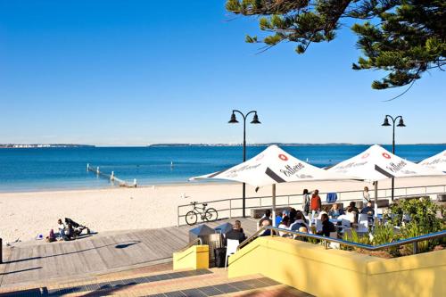 a beach with umbrellas and people sitting on the beach at Beach-Front Apartments in Sydney