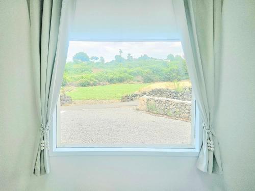 a window with a view of a field at Fongnang Eyeom in Jeju