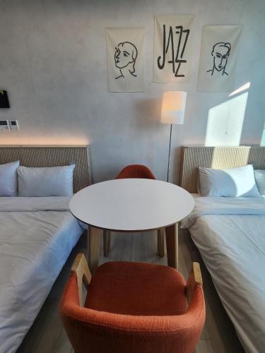 a room with a table and a chair and two beds at 더베이먼트레지던스 in Busan