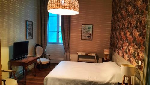 a bedroom with a bed and a desk and a television at aux petits soins in Oloron-Sainte-Marie