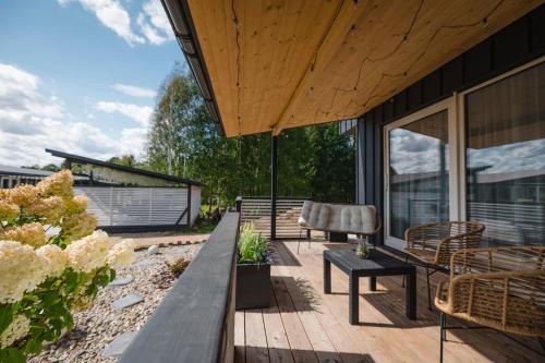 a wooden deck with a bench and chairs on a house at Vila Skodupė 