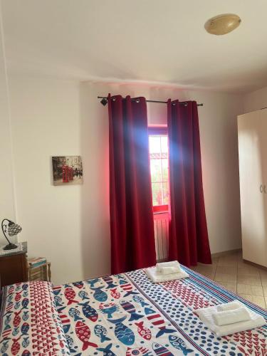 a bedroom with a bed with red curtains and a window at La Maison di Franca in Riace Marina