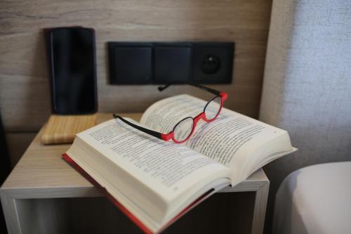 a book with a pair of glasses sitting on a table at Loox Ostrovo- Boutique House-noclegi nad morzem in Ostrowo
