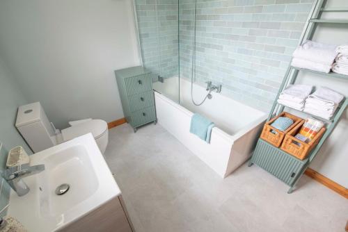 a bathroom with a tub and a sink and a toilet at Corner Cottage in Castlerock
