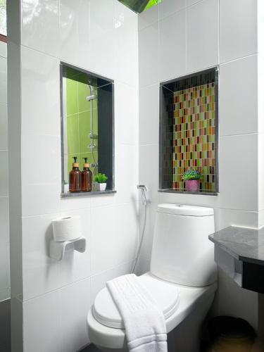 a white bathroom with a toilet and a window at Green Haven Villas With Jacuzzi in Krabi town