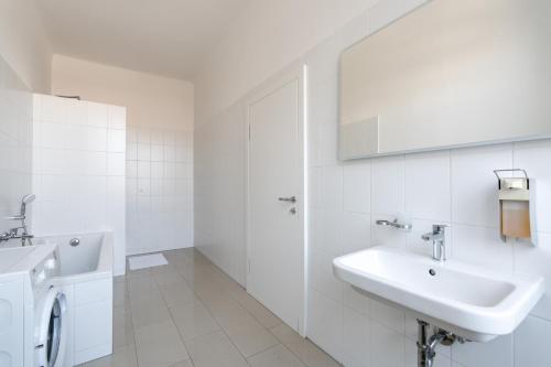 a white bathroom with a sink and a washing machine at Vienna Stay Apartments Schönbrunn in Vienna