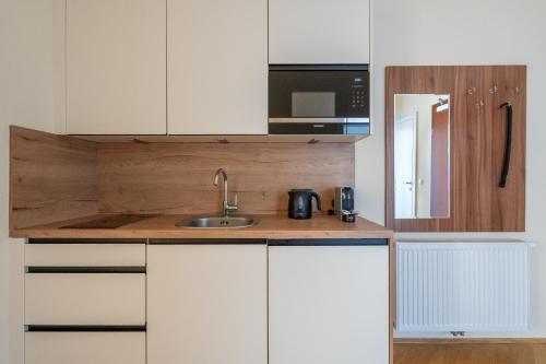 a kitchen with white cabinets and a sink and a microwave at Vienna Stay Apartments Schönbrunn in Vienna