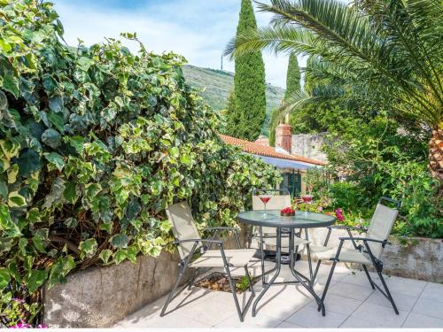 a patio with a table and chairs and a hedge at Dubrovnik Coastal Gem in Dubrovnik