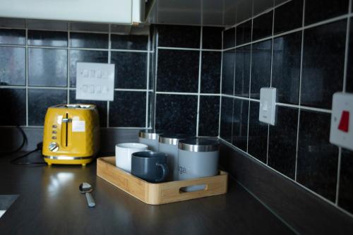 a kitchen with a counter with mugs and a yellow toaster at Spacious home for construction workers and families with parking spaces 2 and half bathroom& ensuite Free wifi in Ashford