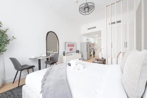 a white bedroom with a bed and a table and chairs at Free housekeeping visits during your stay - StayShort - JVC apartment for 2 people with Swimming Pool in Dubai