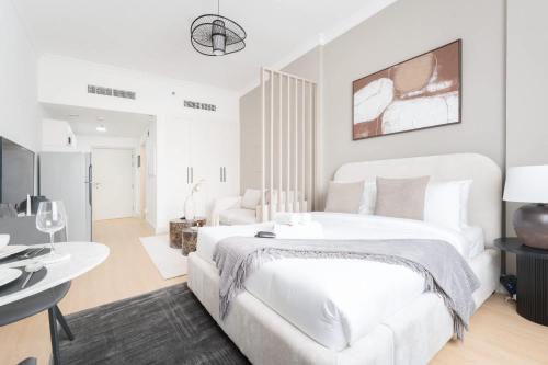 a white bedroom with a large bed and a living room at Free housekeeping visits during your stay - StayShort - JVC apartment for 2 people with Swimming Pool in Dubai