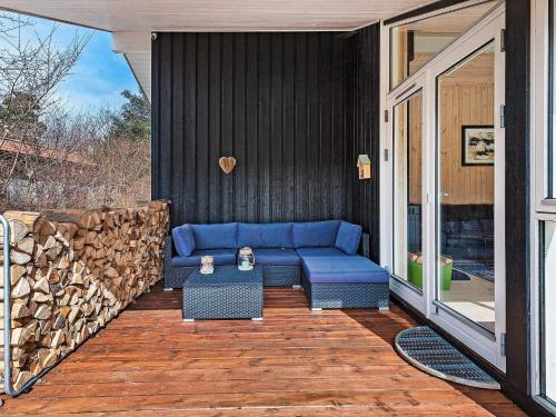 a blue couch on a patio with a pile of wood at 6 person holiday home in Frederiksværk-By Traum in Frederiksværk