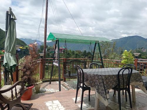 a table and chairs on a deck with a view at Iceberg Hill View in Mussoorie