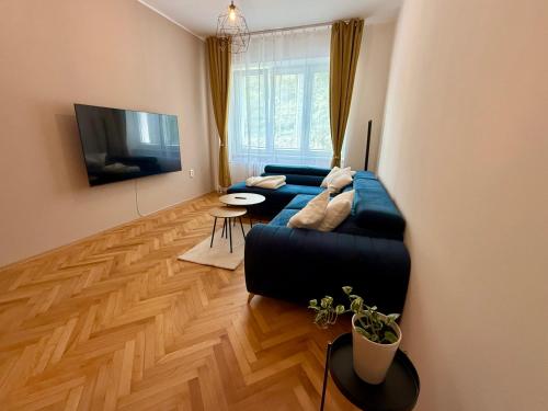 a living room with a blue couch and a television at Ravine Apartments - Parking in Brno
