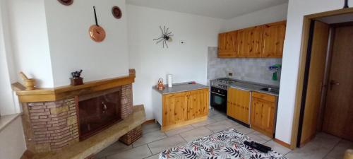 a kitchen with wooden cabinets and a fireplace in it at Appartamento Vecchio Sentiero in Frontignano di Ussita