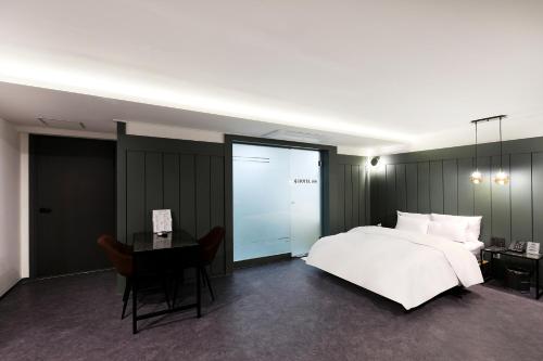a bedroom with a white bed and a desk and a table at Hotel166 in Suwon