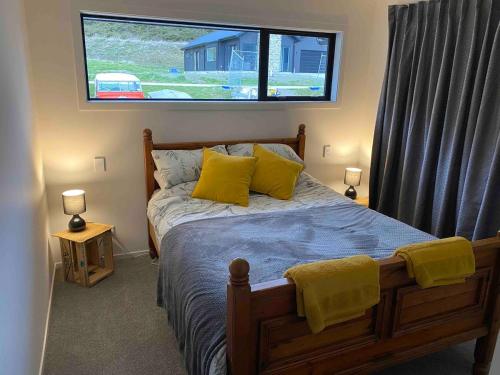 a bedroom with a bed with yellow pillows and a window at House in central Glenorchy in Glenorchy