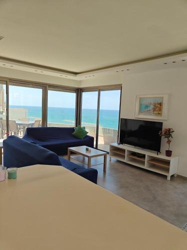 a living room with a blue couch and a flat screen tv at Migdal Luxury Suites - Sea Dream in Netanya