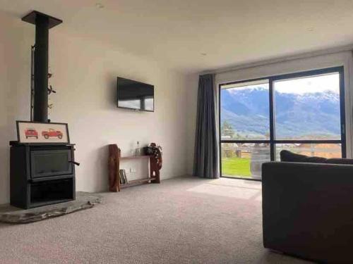 a living room with a fireplace and a large window at House in central Glenorchy in Glenorchy