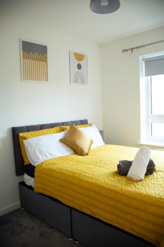 a bedroom with a large bed with yellow sheets and pillows at Spacious home for construction workers and families with parking spaces 2 and half bathroom& ensuite Free wifi in Ashford