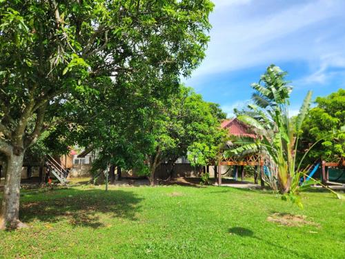 a park with green grass and trees and houses at Le Soleil Kep - Surya Kep in Kep