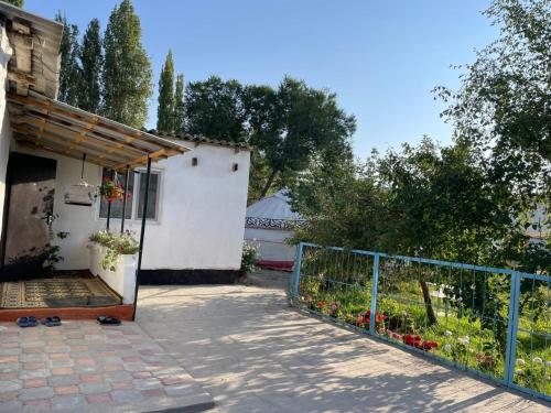 a porch of a house with a fence and flowers at Azem Guest House in Kasymbek