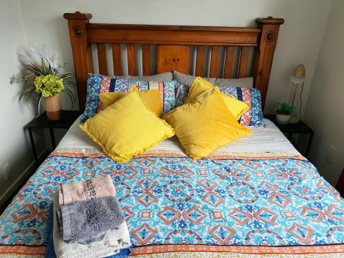 a bed with yellow pillows and a quilt at 3-Bedrooms Home near CBD in Christchurch