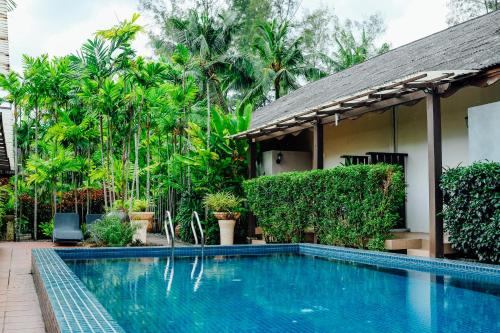a swimming pool in front of a house with trees at Tropical Langkawi in Pantai Cenang