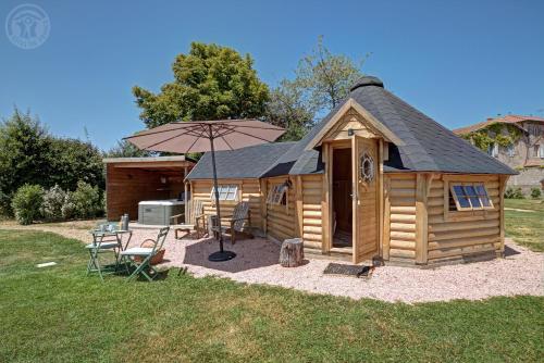 a wooden cabin with an umbrella and a table and chairs at Les Cabanes du Grand Nord in Pradines