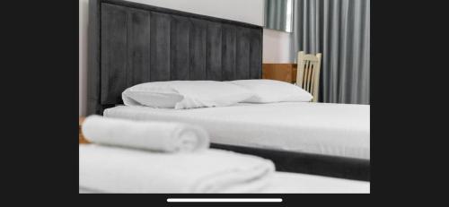 two beds in a hotel room with white sheets and pillows at Brusiano in Vlorë