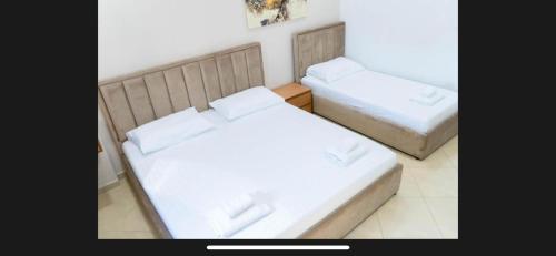 two beds in a room with white sheets at Brusiano in Vlorë