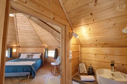 a bedroom in a log cabin with a bed and a sink at Les Cabanes du Grand Nord in Pradines