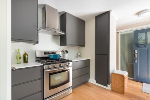 a kitchen with gray cabinets and a stove at Northern Stay in North Vancouver