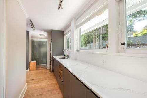 a kitchen with white counters and a large window at Northern Stay in North Vancouver