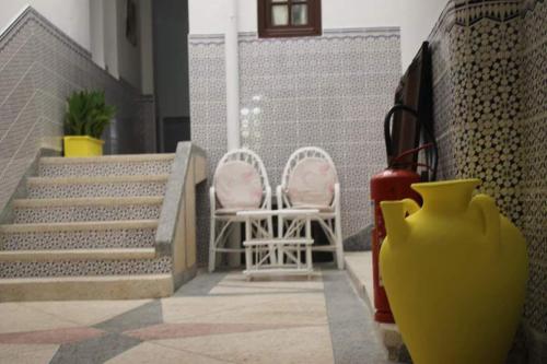 a yellow vase sitting next to two chairs and stairs at HOTELL Elizia in Martil