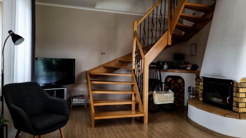 a staircase in a living room with a chair and a television at Ubytovanie Lenka in Osturňa