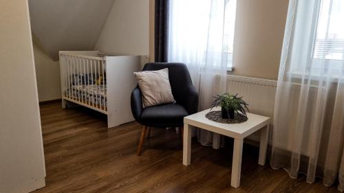 a chair and a table in a room with a crib at Ubytovanie Lenka in Osturňa