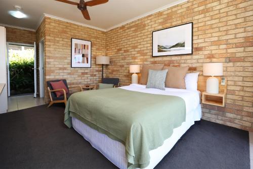 a bedroom with a large bed and a brick wall at Maleny Views Motel in Maleny