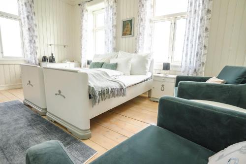 a bedroom with a white bed and two chairs at Sakrisøy Gjestegård - Manor House in Sakrisøy - Solbakken anno 1880 in Reine