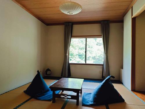 a room with a table and a window with blue pillows at 層雲峡温泉 ホテル雲井 in Kamikawa