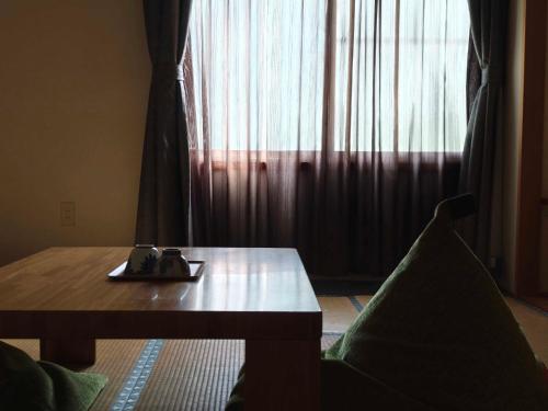 a room with a table and a window with curtains at 層雲峡温泉 ホテル雲井 in Kamikawa