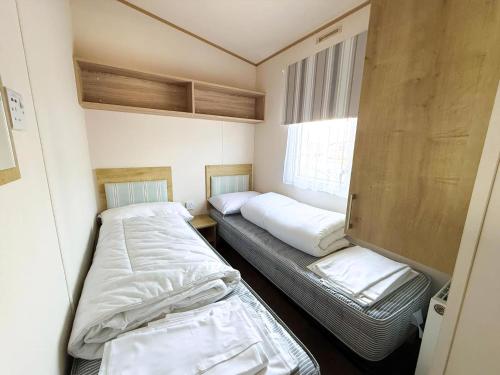 a small room with two beds and a window at Stunning Caravan With Wifi & Decking At St Osyth Beach In Essex Ref 28007Sv in Clacton-on-Sea